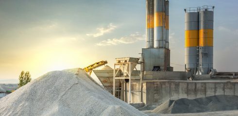 Cement plant with stockpile of cement next to silos