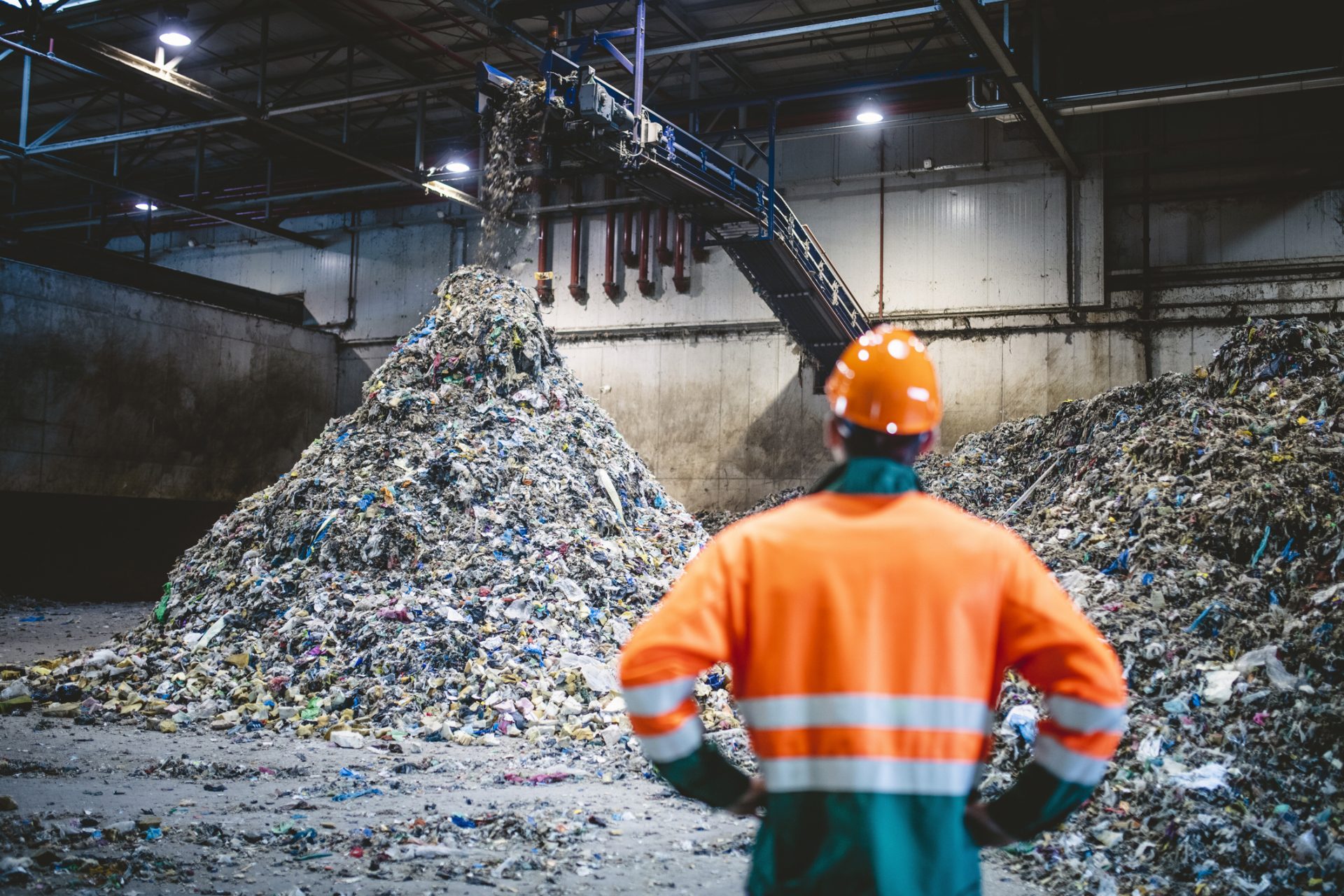 Engineer standing in front of a large pile or recyclable waste